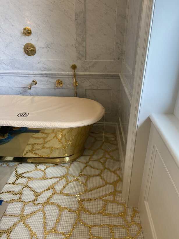 Bathroom with brass fittings and gold mosaic flooring